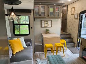 een woonkamer met een bank, een tafel en gele krukken bij Cozy RV Experience w/POOL+SPA Near Lake Conroe in Willis