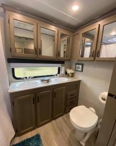 a small bathroom with a toilet and a sink at Cozy RV Experience w/POOL+SPA Near Lake Conroe in Willis