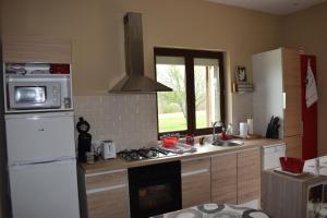 a kitchen with a white refrigerator and a stove top oven at Gîte Cosy Grand confort dans un écrin de verdure in Agudelle