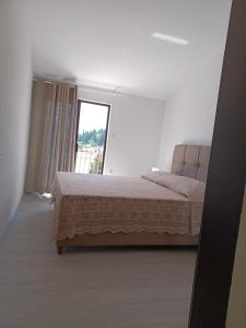 ein Schlafzimmer mit einem Bett und einem großen Fenster in der Unterkunft Apartmani Bartulović in Blace