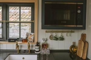 a kitchen with a sink and a microwave at Island Hut - Outdoor bath tub, firepit and water equipment in Saltford