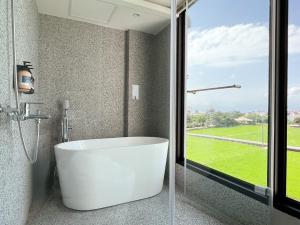 a bathroom with a white tub and a window at 鬧鐘關掉旅店 Alarm Off B&B in Wujie