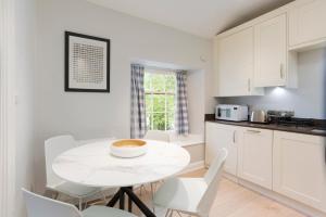 a white kitchen with a white table and chairs at 5 Lowfield, Ambleside in Ambleside