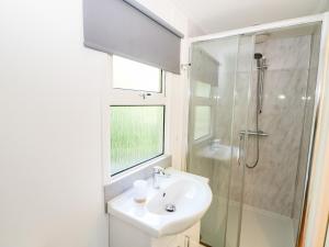 a white bathroom with a sink and a shower at Orchard Lodge in Haywards Heath