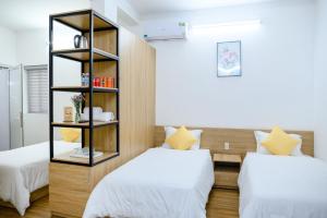 a bedroom with two beds and a book shelf at Familia Hotel in Hue