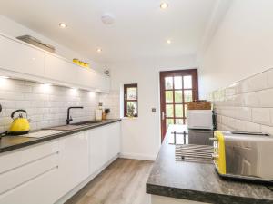 a kitchen with white cabinets and a yellow appliance at The Smithy in Froggatt