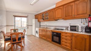 a kitchen with wooden cabinets and a table and a microwave at Altura Vacations T2, Algarve in Altura