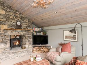 a living room with a stone fireplace and a tv at The Hare's Shack in Kendal