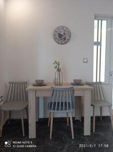uma mesa de jantar com duas cadeiras e um relógio na parede em Sunshine Apartments em Kato Daratso