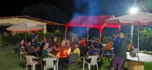 Un groupe de gens assis autour d'un feu la nuit dans l'établissement Hotel Campestre Rocas Del Paraíso, à Machetá