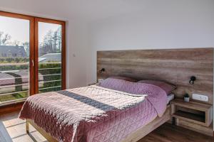 - une chambre avec un lit et une grande fenêtre dans l'établissement Morris Apartamenty, à Chłopy