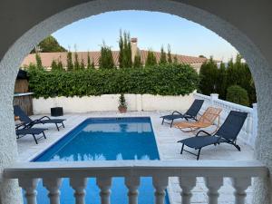 einen Pool auf einer Terrasse mit Stühlen und einem Torbogen in der Unterkunft Villa la Vida in L’Alfàs del Pi