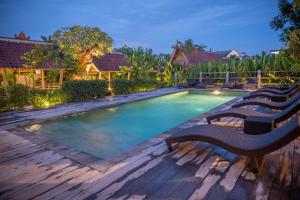 a swimming pool with benches on a wooden deck at Bajalo Cottage Canggu in Canggu
