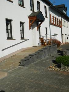 - une terrasse à l'extérieur d'un bâtiment blanc avec des chaises et des tables dans l'établissement Ferienwohnung Bretz, à Dreis