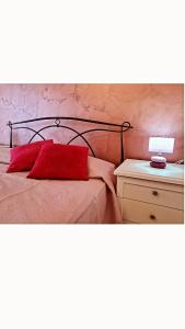 - un lit avec un oreiller rouge et une lampe sur une table de nuit dans l'établissement Da nonna Lina, à Castellammare di Stabia