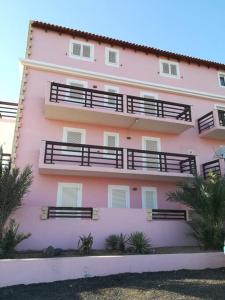 un bâtiment rose avec des balcons sur son côté dans l'établissement Sal Rei apartaments, Boa Vista, free WI-FI, à Sal Rei