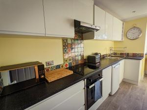uma cozinha com armários brancos e um balcão preto em Beautiful Spacious Central Flat, Pitlochry em Pitlochry