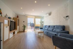 salon z niebieską kanapą i telewizorem w obiekcie HomeHolidaysRentals Benoit - Costa Barcelona w mieście Pineda de Mar
