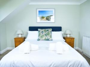 1 dormitorio con 1 cama blanca y 2 mesitas de noche en Ellingham Self-Catering Cottages, en St. Peter Port