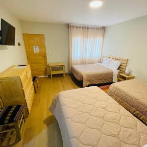 a hotel room with two beds and a television at Alpamayo Casa Hotel - Restaurante in Yungay