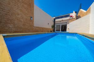 ein großer blauer Pool neben einer Ziegelwand in der Unterkunft HomeHolidaysRentals Benoit - Costa Barcelona in Pineda de Mar