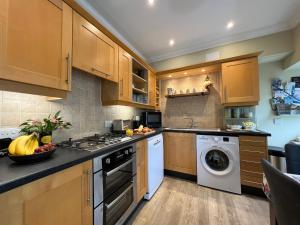 a kitchen with wooden cabinets and a washer and dryer at May Bell Cottage in Dersingham
