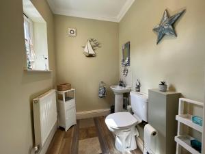 a bathroom with a toilet and a starfish on the wall at May Bell Cottage in Dersingham +18 photos