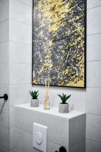 un baño con una pintura y dos plantas en un estante en Sigma Exclusive Apartment en Zadar