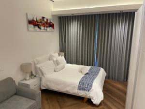 a bedroom with a white bed and a couch at Bridgewater one luxury Apartment in Cape Town