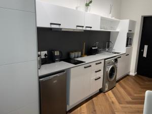 cocina con armarios blancos y lavadora en Bridgewater one luxury Apartment, en Ciudad del Cabo