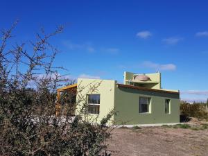 un pequeño edificio verde en medio de un campo en Coralillos en Puerto Madryn