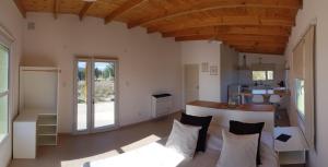 a living room with a table and a kitchen at APA Coralillos - complejo de cabañas con parrillas y estacionamiento cubierto in Puerto Madryn