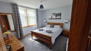 a bedroom with a bed and a table and a window at Deeside Holiday Cottages in Dinnet
