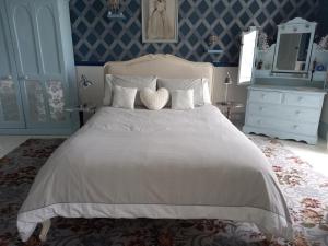 a bedroom with a large white bed with blue walls at Gardenvale Manor House B&B in Stranocum
