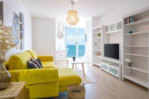 sala de estar con sofá amarillo y TV en Mar y Playa de Martín, 2B, en Las Palmas de Gran Canaria