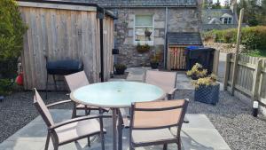a patio with a table and chairs and a fence at Deeside Holiday Cottages in Dinnet