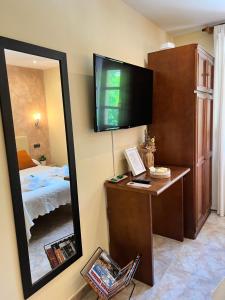 1 dormitorio con espejo, 1 cama y TV en Hostal La Ruta, en Caín