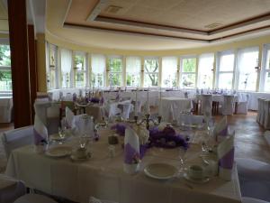 a room filled with tables with white tablecloths and chairs at Waldhaus Colditz Garni in Colditz
