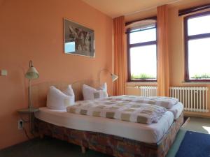 a bedroom with a large bed with two windows at Waldhaus Colditz Garni in Colditz