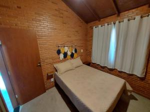 - une petite chambre avec un lit et un mur en briques dans l'établissement Villa da Serra chalé Ibitipoca - 700m do centrinho, à Conceição da Ibitipoca