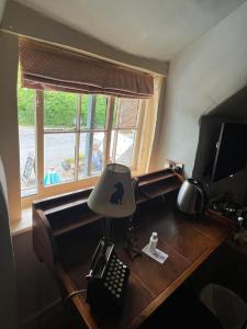 a desk with a lamp and a keyboard and a window at Castle Inn in West Lulworth