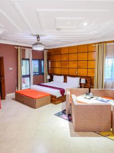 a hotel room with a bed and a couch and chairs at Triple Hill Hotel in Weija