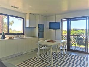 a kitchen with a table and chairs and a balcony at Faraway Falésia in Olhos de Água