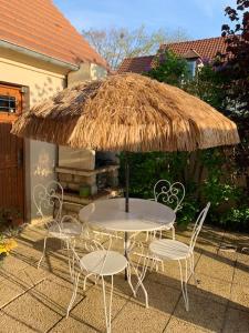 a table and chairs under a straw umbrella at Villa de 4 chambres avec piscine privee terrasse amenagee et wifi a Omerville in Omerville