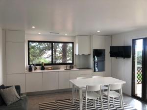 a white kitchen with a white table and chairs at Faraway Falésia in Olhos de Água