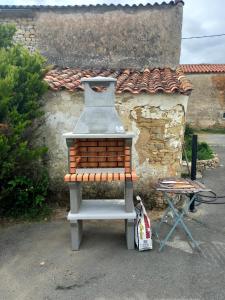 una parrilla sentada frente a un edificio de piedra en GITE ENTRE TERRE ET MER, en Mareuil-sur-Lay