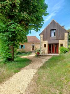 a stone house with a tree and a dirt road at Gîtes Le clos de Veyrignac in Veyrignac