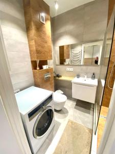 ein Badezimmer mit einer Waschmaschine und einem WC in der Unterkunft Квартира в Авалон на вулиці Чорновола 16є новобудова in Lwiw