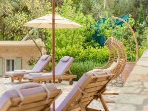 a patio with two lounge chairs and an umbrella at Villa Eva Agni with private pool by DadoVillas in Agní