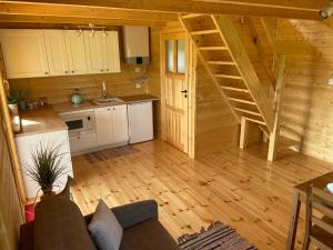 una sala de estar con cocina y una escalera en una cabaña de madera en Domek na Wsi, en Bodzentyn